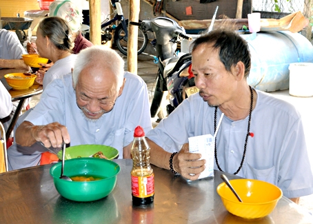 Hai cụ ông vừa ăn cơm vừa nói chuyện tại mái ấm do bà Nguyễn Thị Hồng xây dựng.