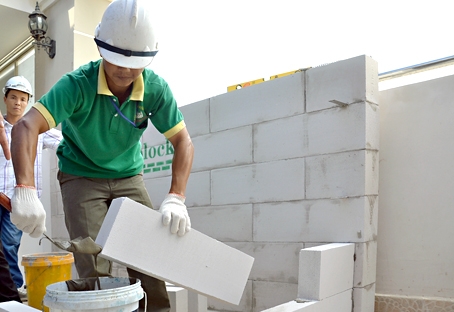 Công nhân Công ty cổ phần Vương Hải (huyện Vĩnh Cửu) xây dựng tường bằng gạch bê tông nhẹ.