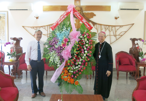 Chairman Dinh Quoc Thai of Dong Nai provincial People’s Committee (L) presents flowers to Bishop Nguyen Chu Trinh.