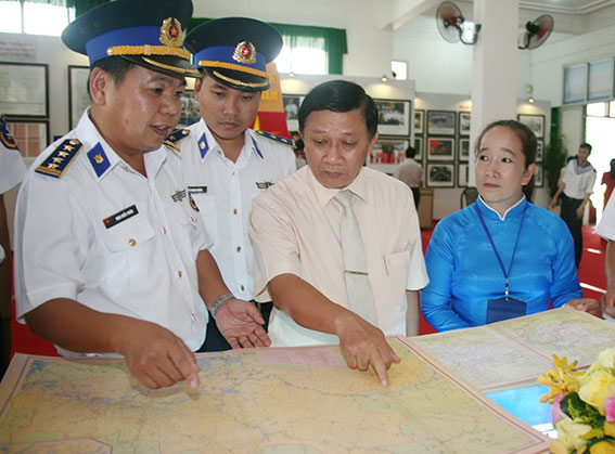 đồng chí Đặng Mạnh Trung, Ủy viên Ban TVTU, Trưởng Ban Tuyên giáo Tỉnh ủy (thứ hai từ phải qua) cùng cán bộ chiến sĩ hải quân xem bản đồ được trưng bày tại triển lãm.