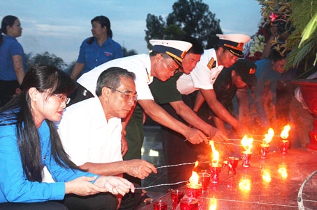 Phó bí thư thường trực Tỉnh ủy Trần Văn Tư (thứ 2 từ trái sang) và các đại biểu cùng thắp nến tri ân các liệt sĩ tại Nghĩa trang liệt sĩ tỉnh đêm 27-7.