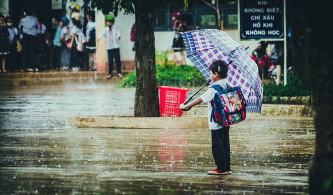 Chiếc ô to thế mới che được hết cậu bé học trò đang chờ mẹ dưới mưa. (Ảnh: Ngô Cảnh Phúc)
