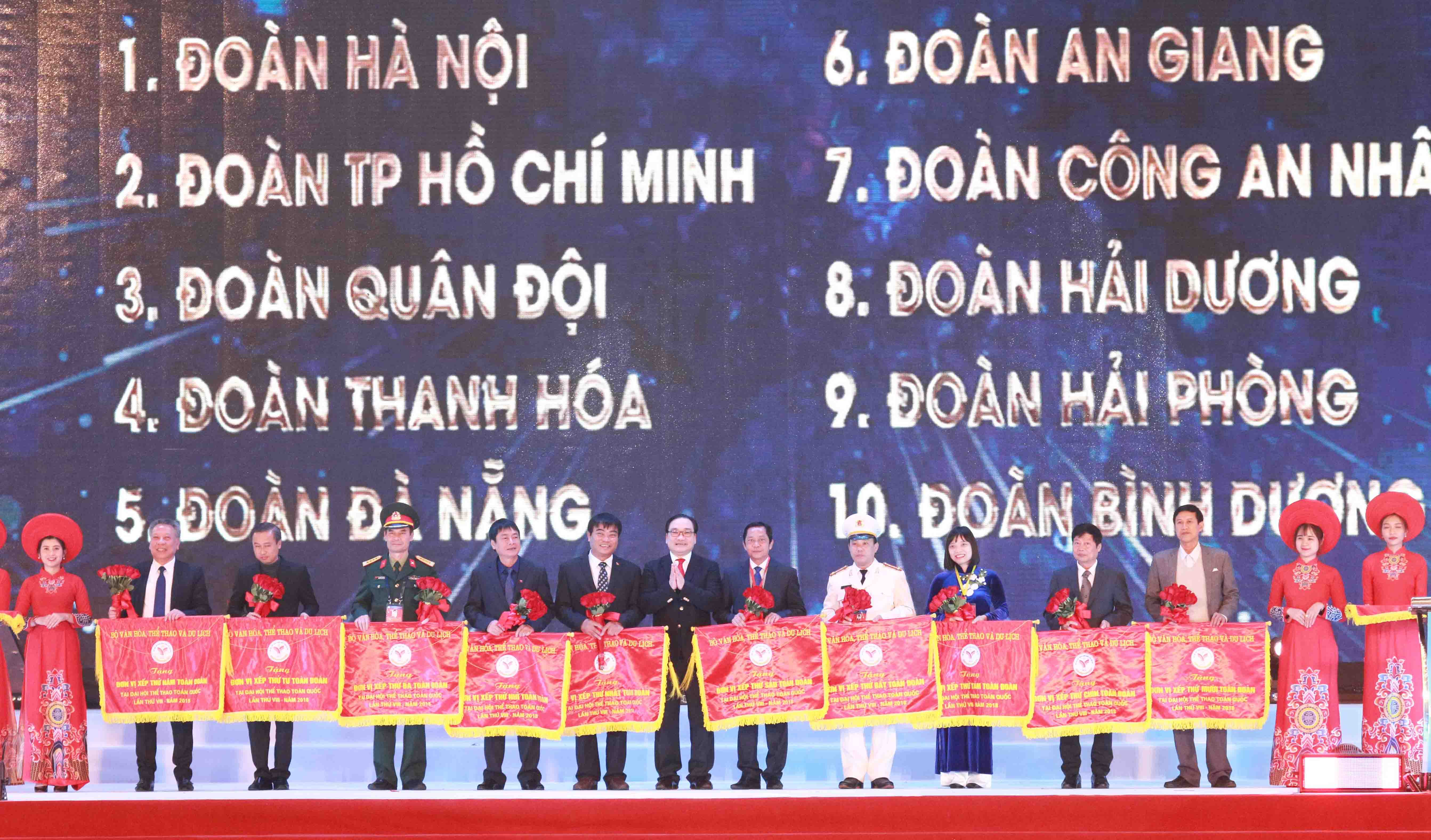 Politburo member and Secretary of Hanoi municipal Party Committee Hoang Trung Hai (C) presents the flags of honour to 10 delegations with excellent achievements at the National Games 2018. (Photo: hanoimoi.com.vn)