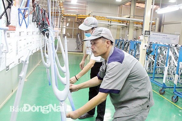 Công nhân Lê Văn Bổn, làm việc tại Công ty hữu hạn cơ khí động lực Toàn Cầu (H.Trảng Bom) kiểm tra chất lượng sơn trên sản phẩm. Ảnh: L.Mai