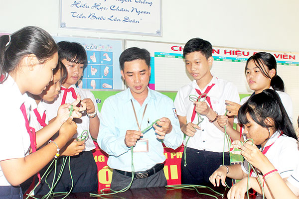 Giáo viên Tổng phụ trách Đội Trường THCS Thạnh Phú (xã Thạnh Phú, H.Vĩnh Cửu) hướng dẫn học sinh thực hành các kỹ năng công tác Đội. Ảnh: Nga Sơn