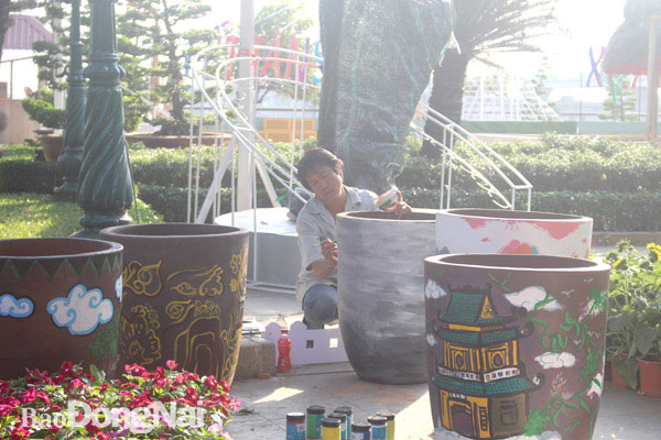 Thầy Nguyễn Đình Sử, giảng viên Trường cao đẳng Mỹ thuật trang trí Đồng Nai đang vẽ các họa tiết trên gốm trưng bày tại đường hoa Nguyễn Văn Trị, TP.Biên Hòa