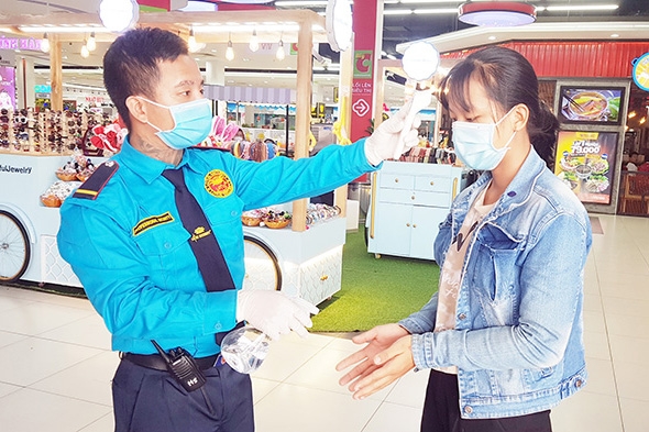 Nhân viên tại một trung tâm thương mại ở TP.Biên Hòa tiến hành kiểm tra thân nhiệt cho khách hàng. Ảnh: H.Hải