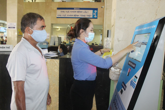 Nhân viên bệnh viện hướng dẫn bệnh nhân đăng ký khám bệnh bằng thẻ khám bệnh 2 trong 1 tại ki ốt.