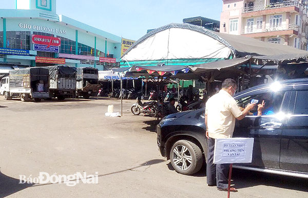 Nhân viên của Ban quản lý chợ Phương Lâm (H.Tân Phú) kiểm tra thân nhiệt của người dân trên các phương tiện cơ giới từ địa phương khác đến trước khi vào chợ. Ảnh: C.T.V