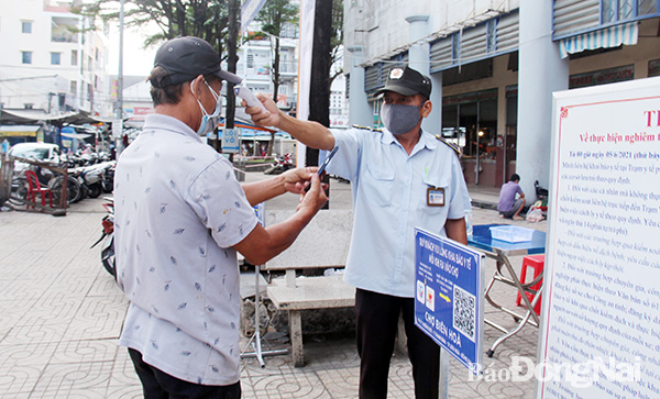 Nhân viên của chở kiểm tra thân nhiệt cho khách hàng trước khi vào chợ