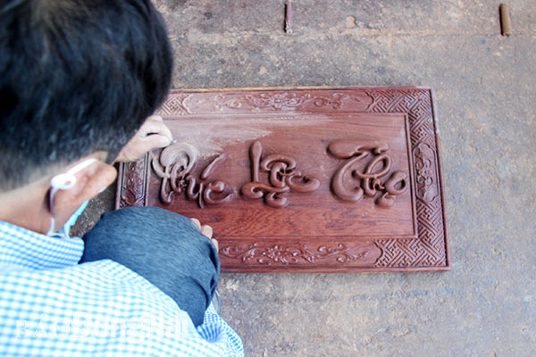 5. Một nghệ nhân đang hoàn thiện bức bình phong “Phúc - Lộc - Thọ” bằng gỗ cẩm lai