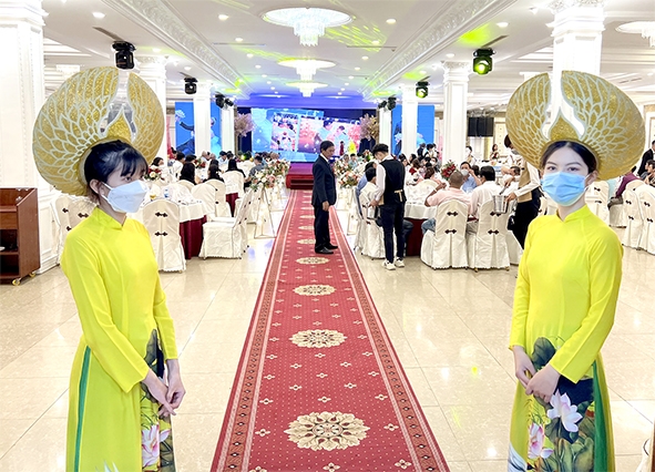 Nhân viên lễ tân đón khách đến dự tiệc cưới được tổ chức vào đầu tháng 3-2022 tại một nhà hàng tiệc cưới. Ảnh: H.Hà