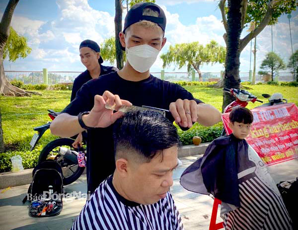 Anh Hoàng Anh chăm chút mái tóc cho ông Năm Thân ở chợ Biên Hòa. Ảnh: Đoàn Phú