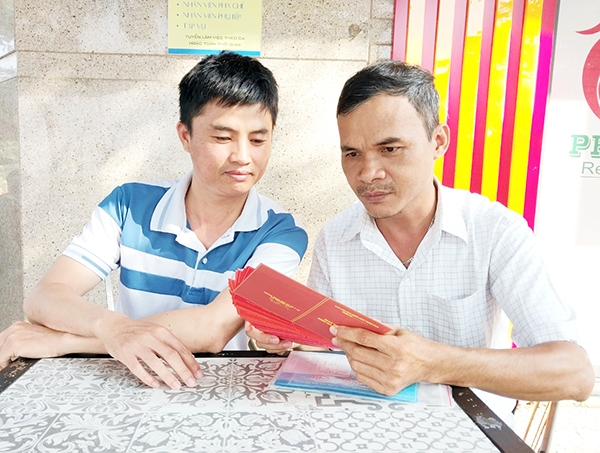 Ông Phạm Quỳnh Uyển (phải) với giấy chứng nhận các lần hiến máu tình nguyện