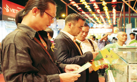 Các đại sứ hàng Việt là đạo diễn Đoàn Khoa (đứng đầu) và diễn viên Quyền Linh đang xem sản phẩm mới tại hội chợ.