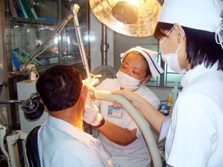Điều dưỡng Phạm Kim Vui (giữa) đang đốt mụn cóc cho bệnh nhân.