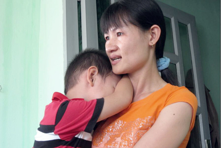 Chị Nguyễn Thị Hồng, vợ của Trung úy Lê Trần Phương, bế con xúc động trong ngôi Nhà đồng đội mới được Bộ Tư lệnh Vùng 2 Hải quân trao tặng.