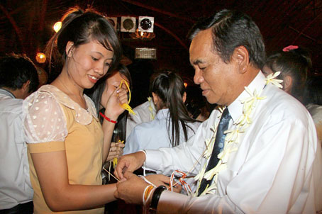 Bí thư Tỉnh ủy Trần Đình Thành thực hiện nghi thức buộc chỉ cổ tay cho sinh viên Lào. Ảnh: C. Nghĩa