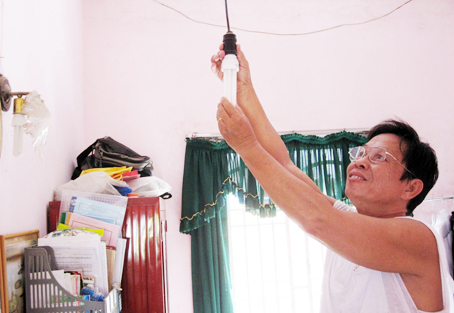 Ông Võ Văn Cường kiểm tra bóng đèn compact trong nhà.