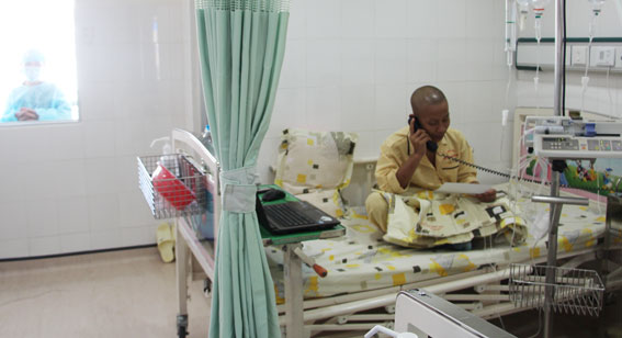 Em Cao Xuân Hiệp trò chuyện với người thân qua đường dây điện thoại từ phòng vô trùng tuyệt đối của Bệnh viện truyền máu và huyết học. Ảnh: P. Liễu