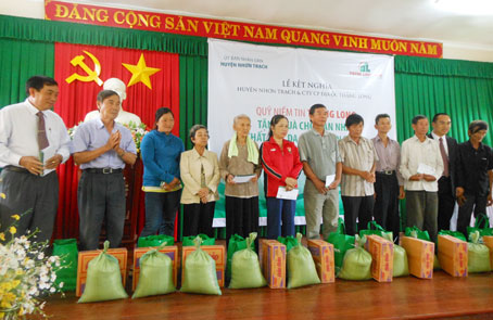 Lãnh đạo huyện Nhơn Trạch (bìa trái) và lãnh đạo công ty Thang Long Real trao quà cho các gia đình nạn nhân chất độc da cam