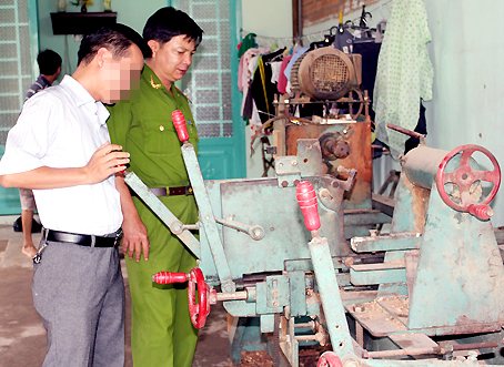 Đại diện Công an phường Long Bình xem xét máy tiện gỗ của anh S.L. (phường Long Bình), được đầu tư từ nguồn vốn hỗ trợ của Quỹ Doanh nhân với an ninh trật tự.