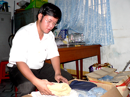 Anh Trần Minh Hải đang sắp xếp lại những bộ quần áo cũ quyên góp được để chuẩn bị gửi đến trẻ em nghèo.