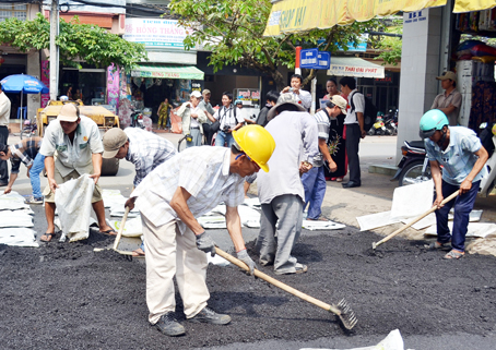 Công nhân sử dụng vật liệu Carboncor Asphalt để thảm mặt đường Nguyễn Văn Nghĩa, phường Quang Vinh, TP.Biên Hòa. Ảnh: V.Nam