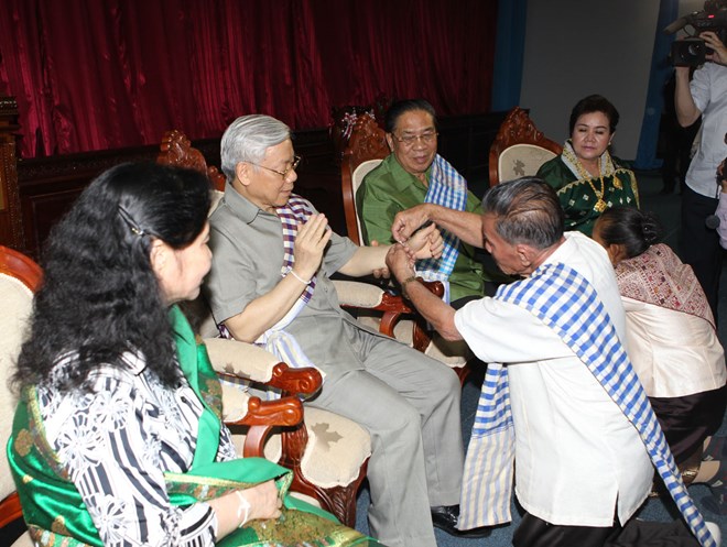 Tổng Bí thư Nguyễn Phú Trọng và Phu nhân cùng Tổng Bí thư, Chủ tịch nước Lào Chummaly Sayasone và Phu nhân dự Lễ buộc chỉ cổ tay chúc phúc. (Ảnh: TTXVN)
