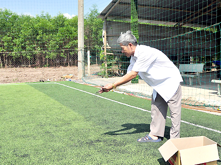Ông Trịnh Hồng Sơn chăm sóc sân cỏ trước khi trận bóng bắt đầu.