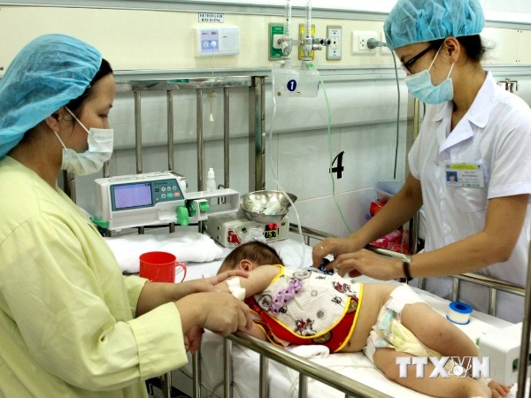 Nhân viên y tế điều trị cho trẻ mắc bệnh mùa Hè. (Ảnh: TTXVN)