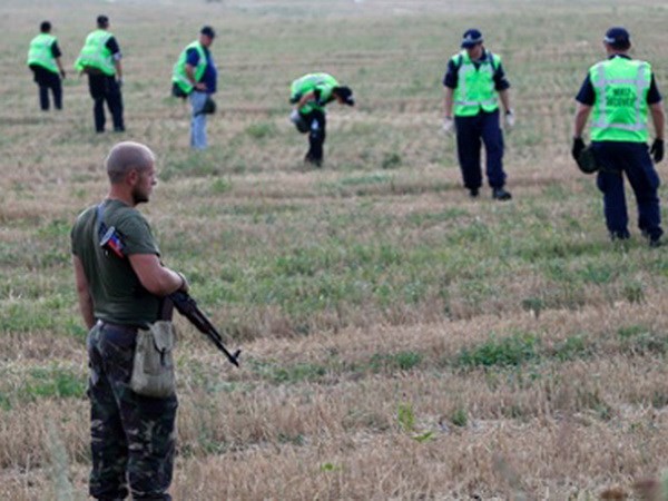 Một tay súng ly khai đứng gác trong khi các chuyên gia từ Australia và Hà Lan kiểm tra hiện trường MH17 gần làng Rozsypne, Donetsk. (Nguồn: Reuters)