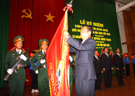 Đồng chí Trần Đình Thành thừa ủy quyền của Chủ tịch nước gắn Huân chương lao động hạng Nhất lên lá cờ truyền thống của Đảng bộ, quân và dân huyện Nhơn Trạch.