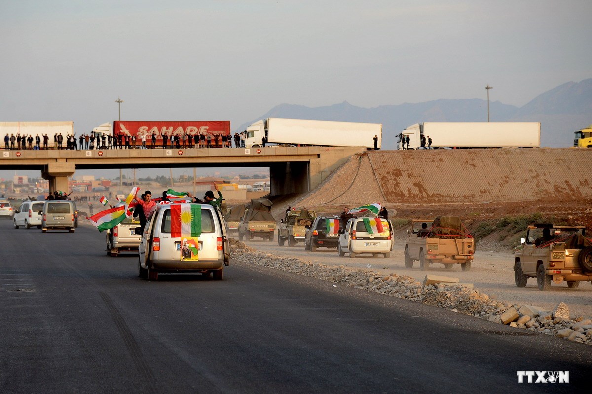Những người Kurd ở Thổ Nhĩ Kỳ vẫy cờ chào mừng đoàn xe chiến binh người Kurd (bên phải) đang vượt qua cửa khẩu Habur tiến về thị trấn Kobane ngày 29/10. (Nguồn: AFP/TTXVN)