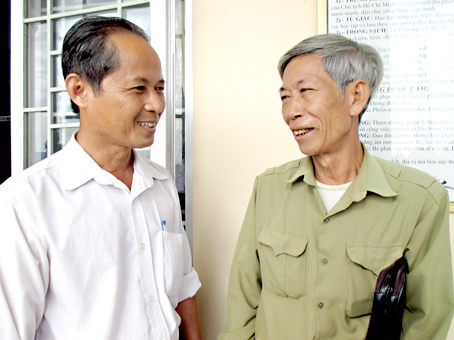 Ông Mai Văn Lai (phải) trao đổi công tác với cán bộ Đảng ủy thị trấn Vĩnh An. Ảnh: Đ.Phú