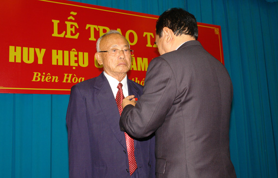 Đồng chí Trần Đình Thành – UVTW Đảng, bí tư Tỉnh Ủy gắn huy hiệu 65 năm tuổi đảng cho đồng chí Phan Văn Trang nguyên Bí thư Tỉnh Ủy Đồng Nai.
