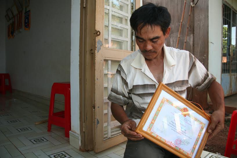 ông Thổ Tùng (dân tộc Chơro, xã Hàng Gòn) lau chùi những tấm giấy khen mà gia đình ông đạt được qua các hội thi văn nghệ, thể thao do thị xã và tỉnh tổ chức để trưng bày trong nhà trong dịp tết này.