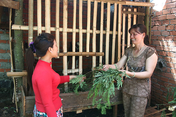 Bà  Lê Thị Huệ (bên phải) hướng dẫn kỹ thuật chăm sóc dê cho một hộ dân mới chăn nuôi dê lần đầu.