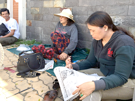 Phụ huynh ở huyện Long Thành đọc thông tin về kỳ thi trên báo trong lúc chờ con thi môn ngoại ngữ tại điểm thi Trường đại học sư phạm kỹ thuật TP.Hồ Chí Minh.