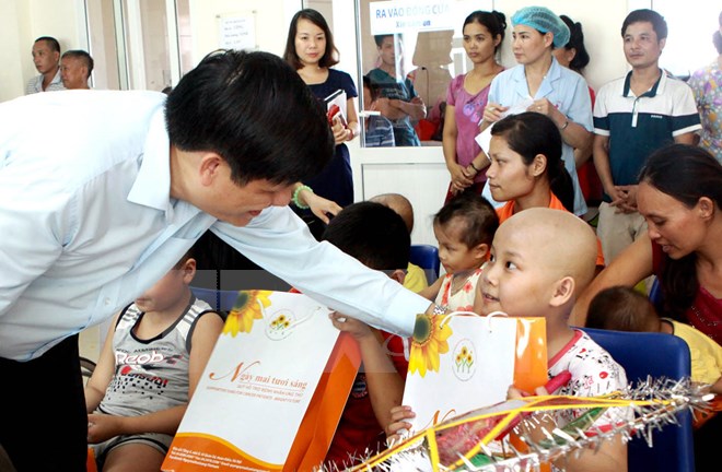 Thứ trưởng Bộ Y tế Nguyễn Thanh Long trao quà cho các bệnh nhi ung thư trong sự kiện diễn ra vào tháng 9/2015.(Ảnh: Dương Ngọc/TTXVN)