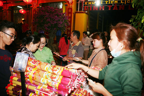 Người dân mua nhang để vào dâng hương trong đêm giao thừa tại Di tích quốc gia Đình Tân Lân trong đêm giao thừa.