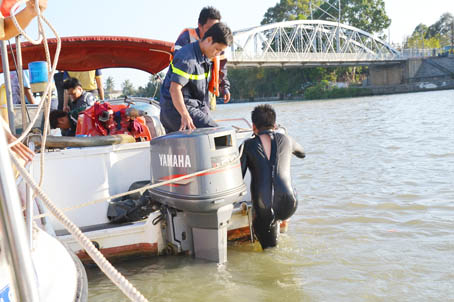 Nhóm thợ lặn đang xuống sông để xác định nơi tàu đẩy xà lan bị chìm.