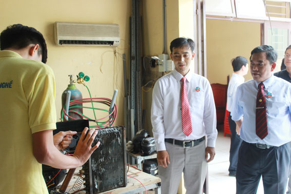 Đồng chí Huỳnh Văn Tới (bìa phải) đi thăm các lớp thực hành của Trường Trung cấp nghề Hòa Bình