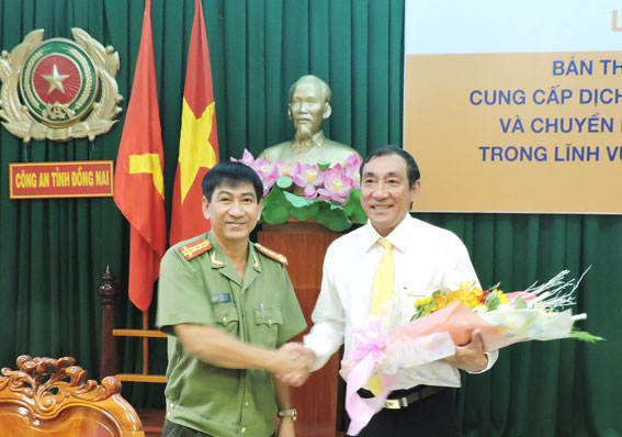 Phó giám đốc Công an tỉnh Bùi Ngọc Danh (trái) tặng hoa cho ông Nguyễn Thành Nhân, Giám đốc Bưu điện tỉnh.