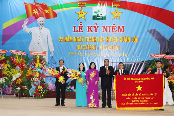 Phó bí thư thường trực Tỉnh ủy Trần Văn Tư (thứ ba từ phải qua) và Phó chủ tịch UBND tỉnh Nguyễn Hòa Hiệp (thứ ba từ trái qua) trao bức trướng của UBND tỉnh cho Đảng bộ và  nhân dân huyện Xuân Lộc
