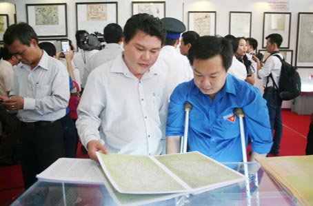 Dù việc đi lại khó khăn và phải dùng đến nạng chống nhưng anh Lê Duy Nhiên, chuyên viên Văn phòng Tỉnh ủy (phải), vẫn cố gắng đến tham quan triển lãm bản đồ và trưng bày tư liệu “Hoàng Sa, Trường Sa của Việt Nam - những bằng chứng lịch sử và pháp lý” được tổ chức tại Bảo tàng Đồng Nai.