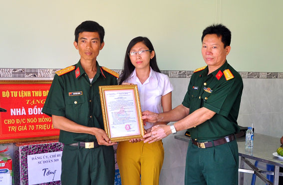  Đại tá Nguyễn Minh Chiến Phó Chính ủy Sư đoàn 309 trao quyết định tặng nhà đồng đội cho vợ chồng thượng úy Ngô Hồng Quang.