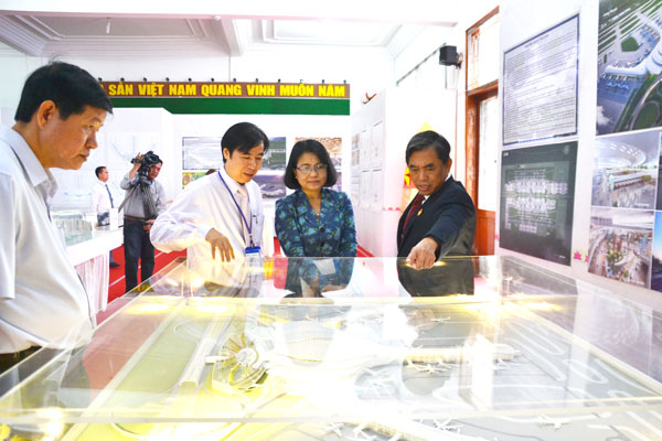 Chủ tịch UBMTTQ tỉnh Huỳnh Văn Tới (phải) đang thảo luận về một mô hình sân bay tại khu trưng bày.