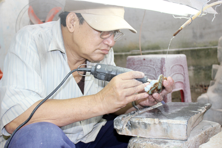 Ngày ngày, người thợ già Trần Văn Luyến vẫn tỉ mỉ hoàn thiện những tác phẩm điêu khắc đá. Ảnh: Lê Quyên