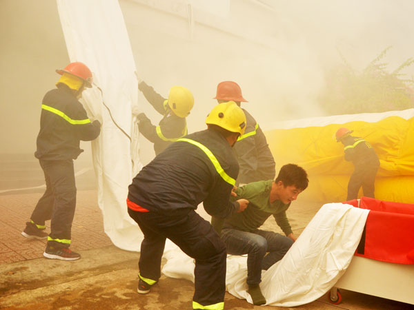 Một người vừa thoát khỏi đám cháy nhờ sử dụng đường ống trượt thoát nạn do lực lượng cứu nạn cứu hộ đưa tới.